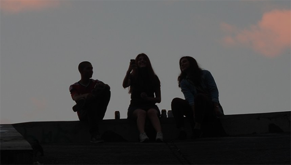 Teenagers sitting on a roof in silhouette